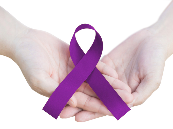 woman's hands holding purple ribbon