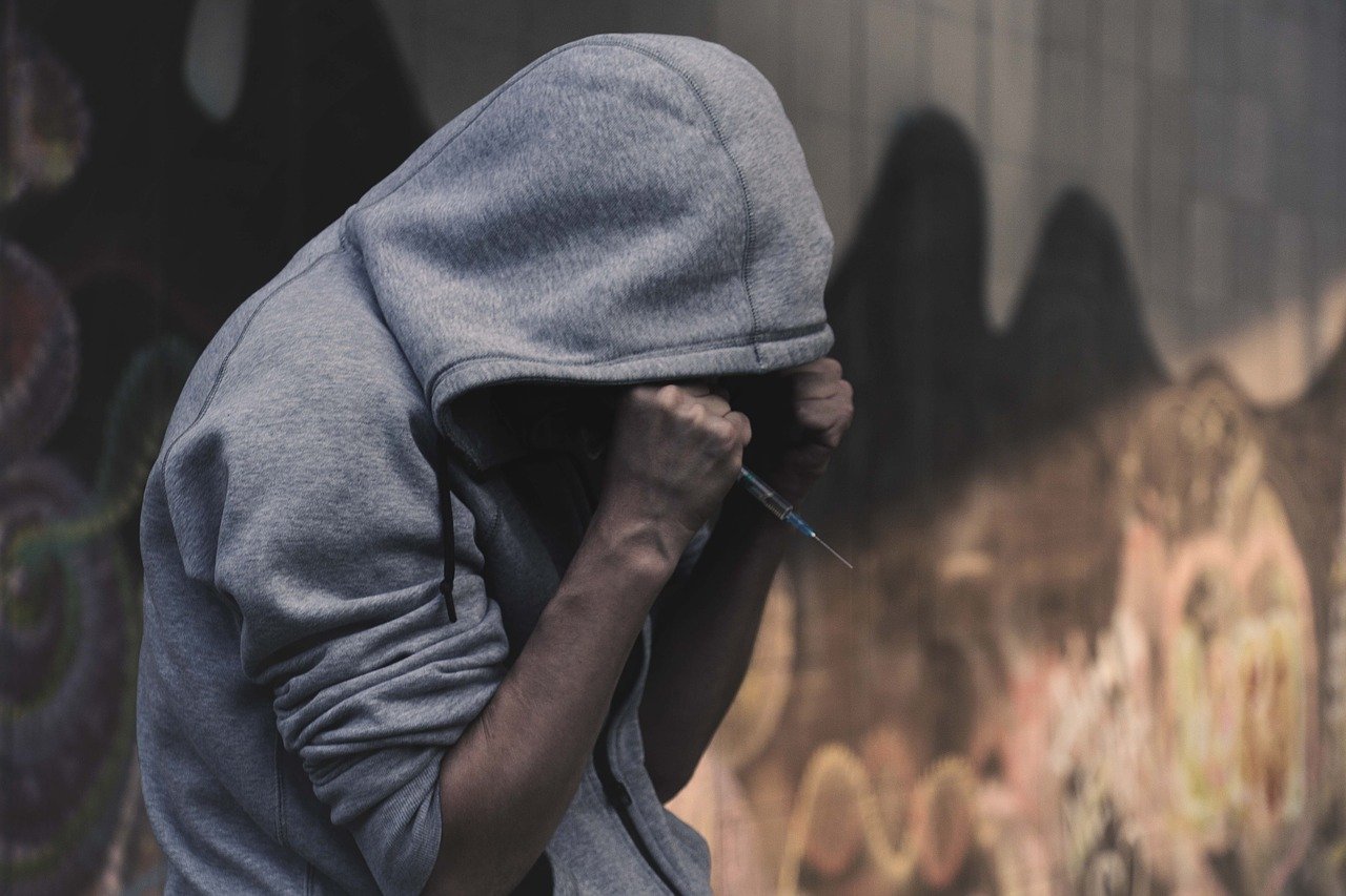 Person in a hoodie with syringe