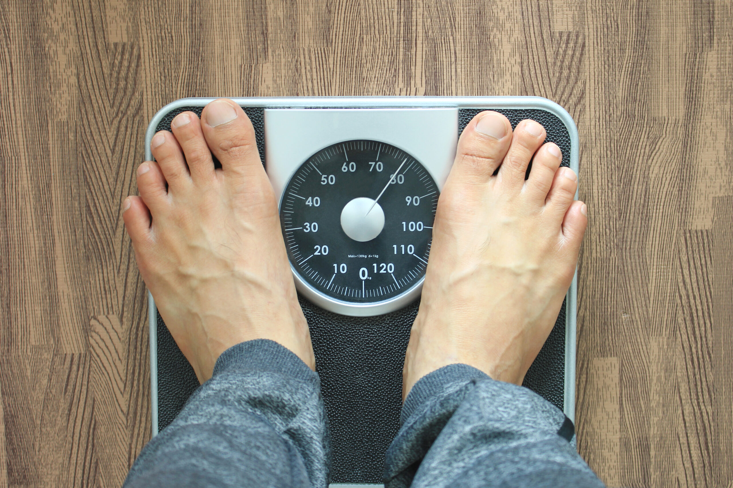white man's feet standing on weight scale