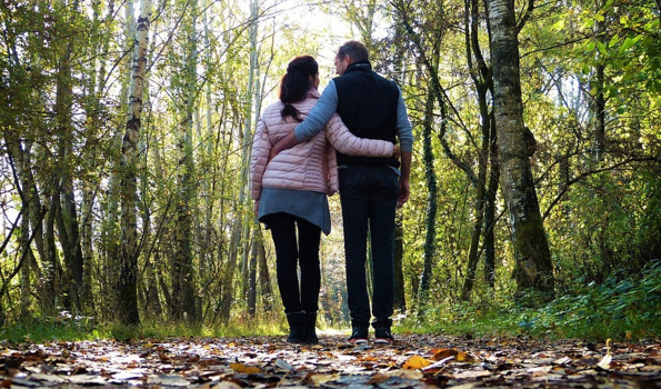 woman and man walking in the woods with arms around each other