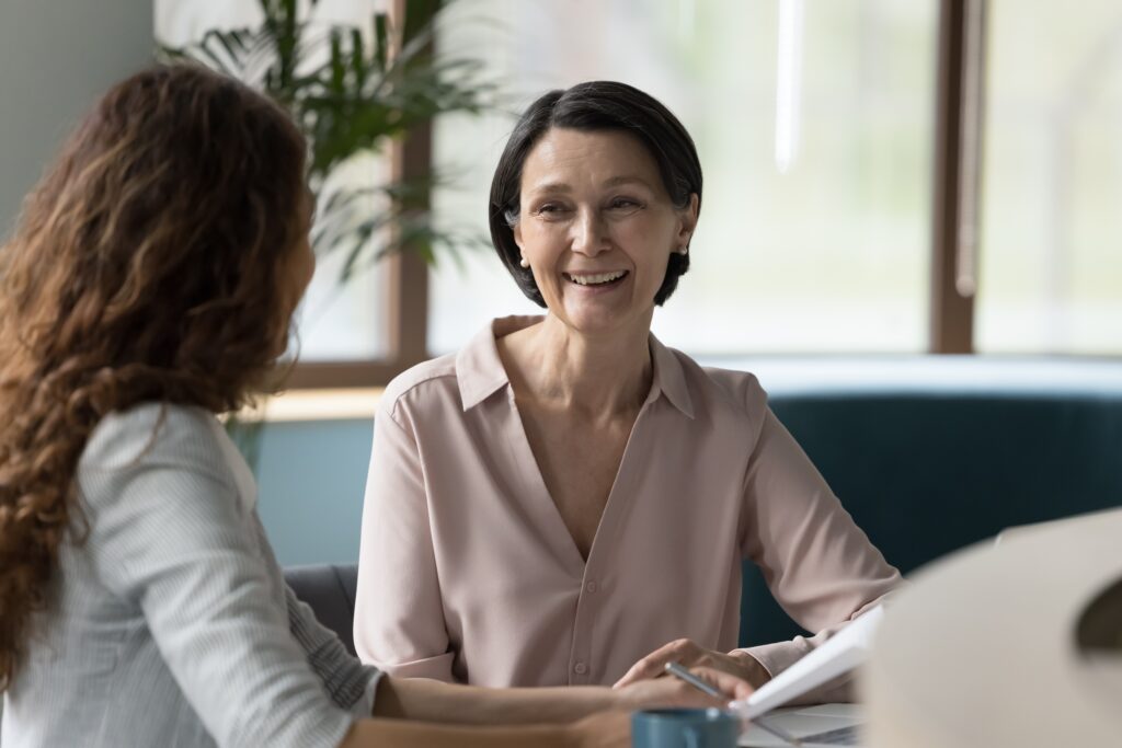 Two women smiling and talking to each other in an office setting